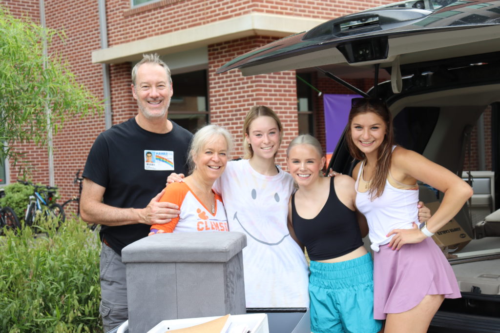 Parents posing with daughter and roommates while unloading car