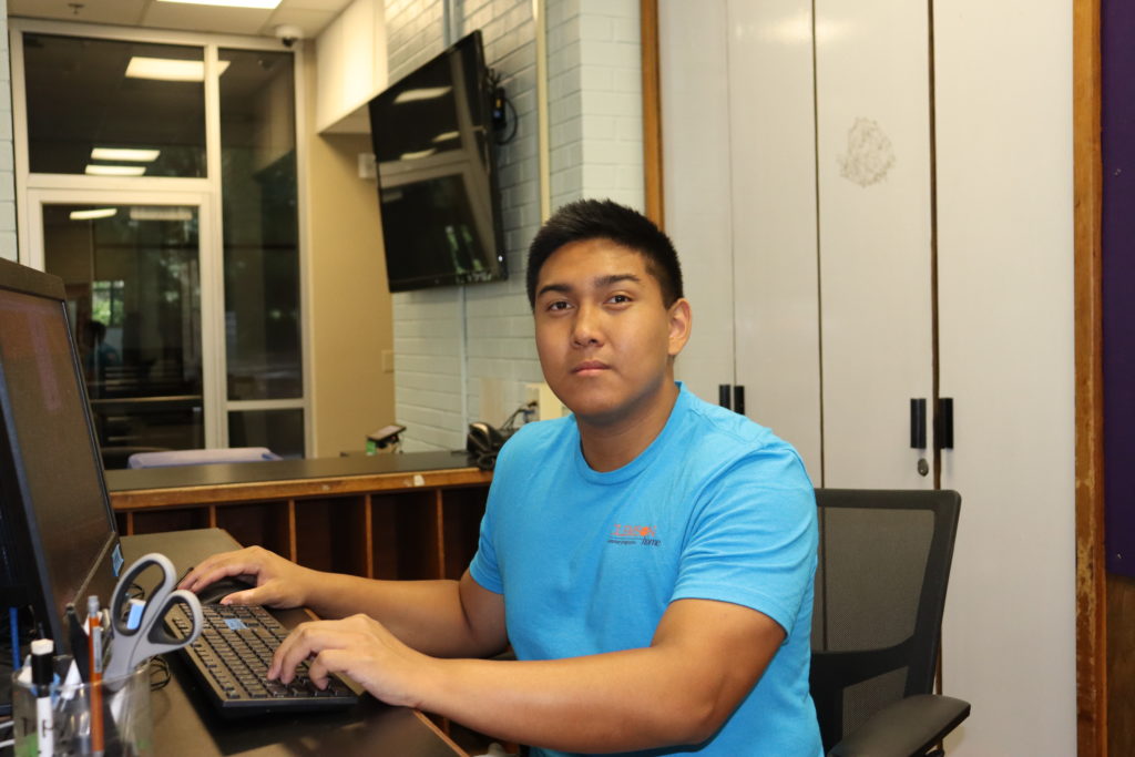Summer Programs student desk assistant at front desk working on computer
