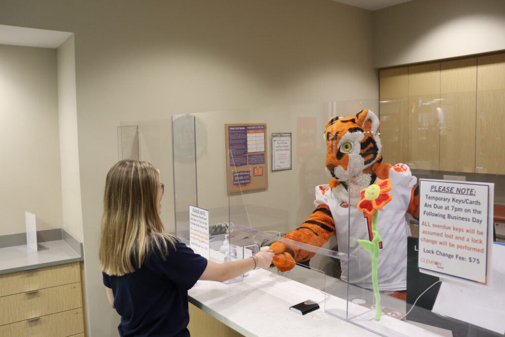 Tiger handing key to student at front desk